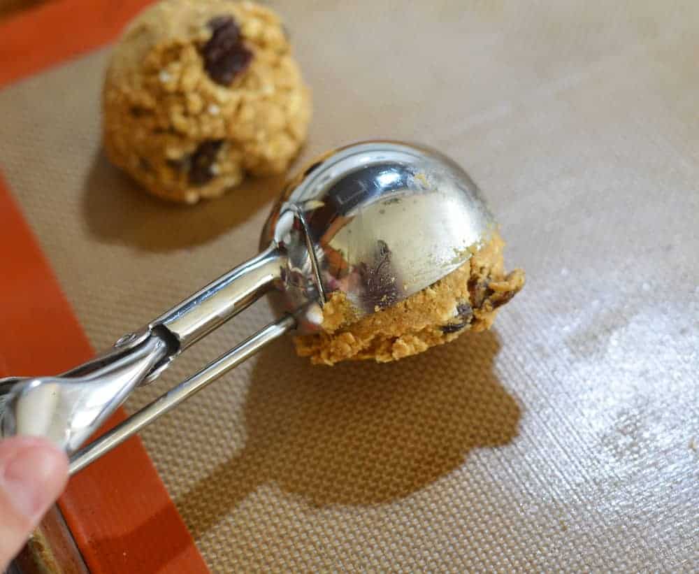 Using an ice cream scoop to for batter into Big & Chewy Vegan Oatmeal Raisin Cookies