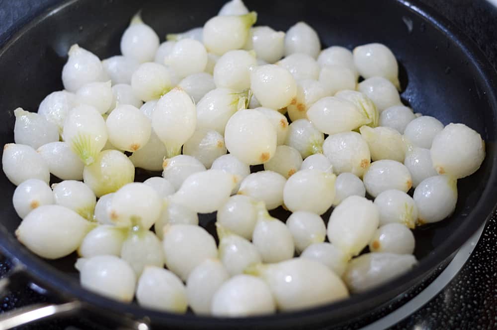 Frozen Pearl Onions in a Black Non Stick Pan
