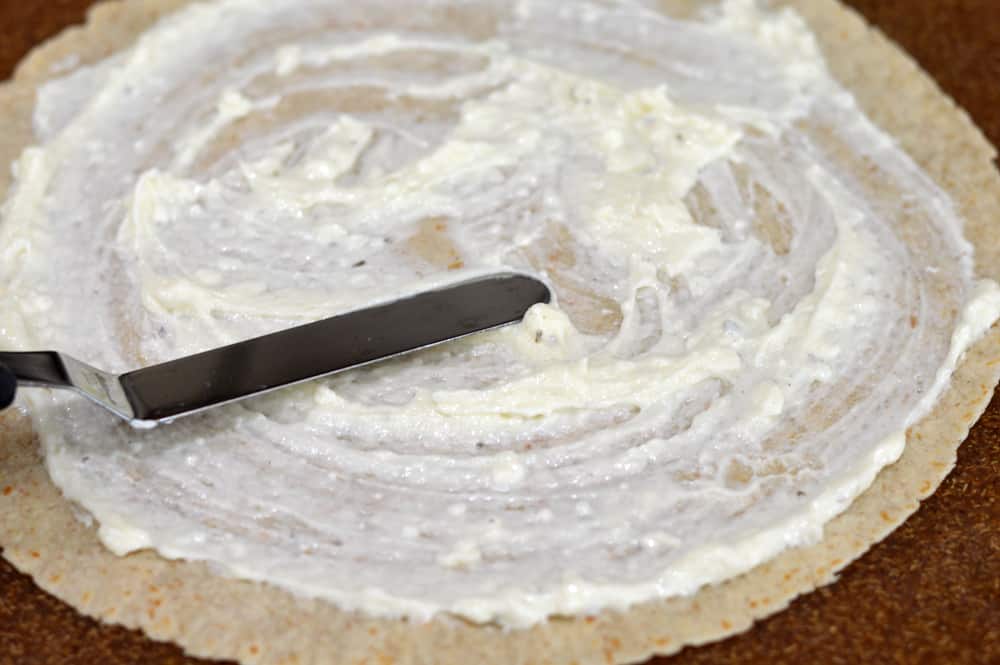 Spreading Cream Cheese Ranch Mixture on a Tortilla for Vegan Buffalo Crispy Tender Roll Ups
