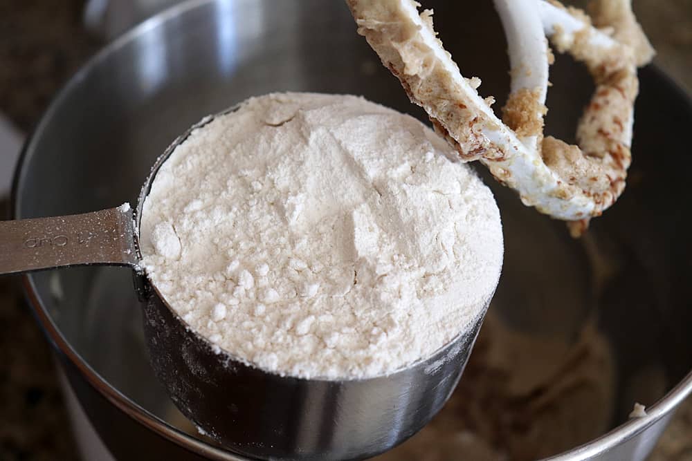 Adding flour to the bowl of an electric mixer