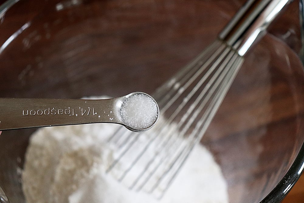 Adding salt to a glass bowl with a whisk