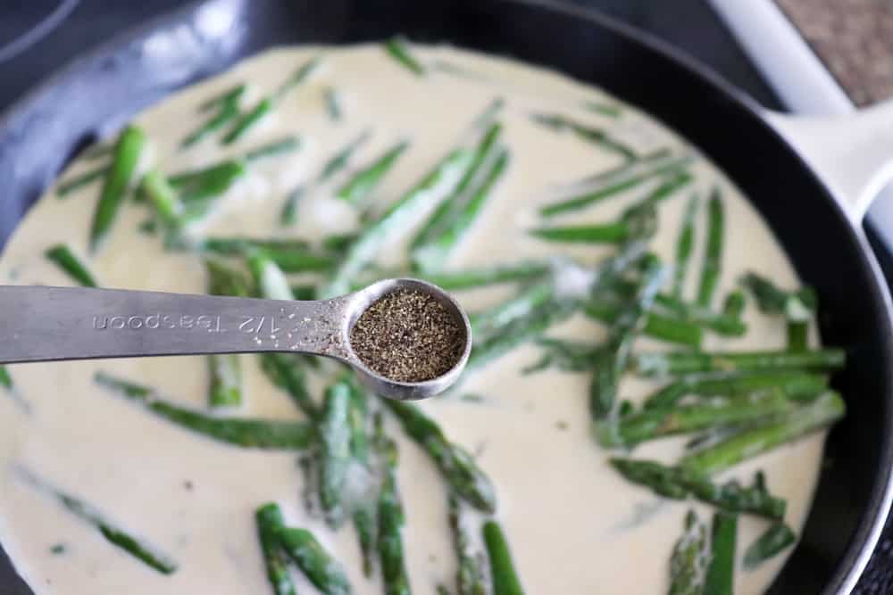 Adding pepper to the asparagus