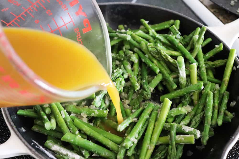 Adding broth to the asparagus