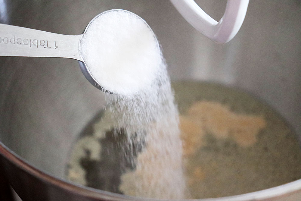 Adding yeast and sugar to water in a mixer